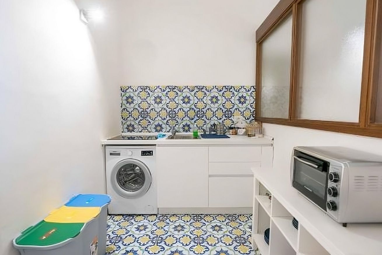 Une cuisine compacte équipée d’un lave-linge, d’un four à micro-ondes et d’un évier.