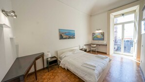 A bedroom with a bed, a desk, a chair, a nightstand, and a painting on the wall. - Arcoleo Prestige 2 By Dimorra (NAPOLI)