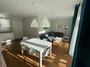 A modern living space with a dining area, sofa, and kitchen.