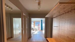 A modern hallway with wooden flooring, a bench, and a wooden wall with hooks. - Exclusive Apartment With Scenic View (Bad Kleinkirchheim)