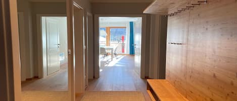 Un couloir moderne avec un plancher en bois, un banc et un mur en bois muni de crochets.