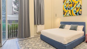 A bedroom with a bed, curtains, a wall-mounted air conditioner, and a patterned rug. - Cognetti Suite 2 in Bari (Bari)