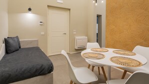 A modern bedroom with a bed, bedside table, and a small table with chairs. - Cognetti Suite 2 in Bari (Bari)