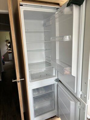 Een open koelkast met meerdere planken en een vriesvak.