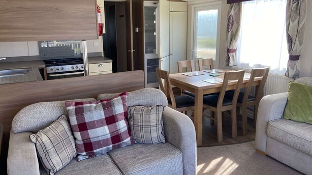 A compact RV interior with a kitchenette, dining area, and seating. - Butlins-skegness-luxury 8 Berth Caravan-dog Friend (Skegness)