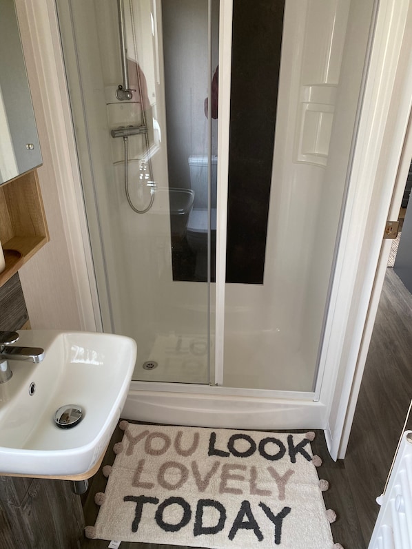 A bathroom with a glass shower enclosure, a white sink, and a rug with the text "YOU LOOK LOVELY TODAY". - 8 Berth Luxury Caravan On Butlins, Skegness D/F (Skegness)