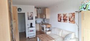 A compact living space with a kitchenette, a sofa, a coffee machine, and wall art.