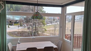 A room with a large window, a table, chairs, and a hanging light fixture. - FeWo Eulenhorst - Holiday enjoyment in the vacation resort at Schluchsee (with pool) (Schluchsee)