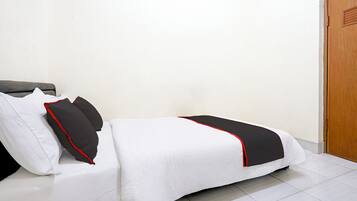 A neatly made bed with white bedding and black accents, a wooden door, and a tiled floor.