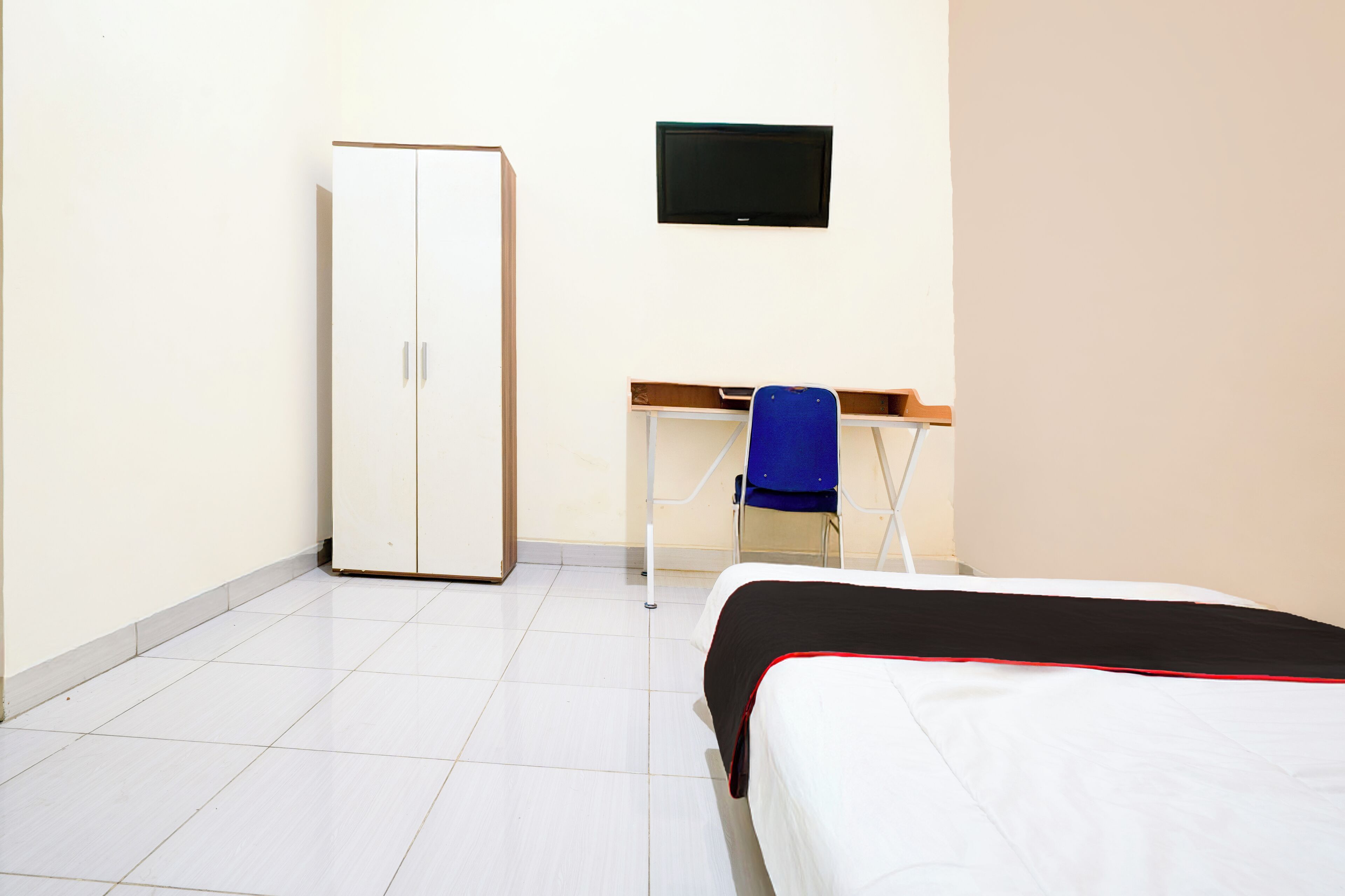 Een slaapkamer met een bed, een bureau, een stoel en een kledingkast.
