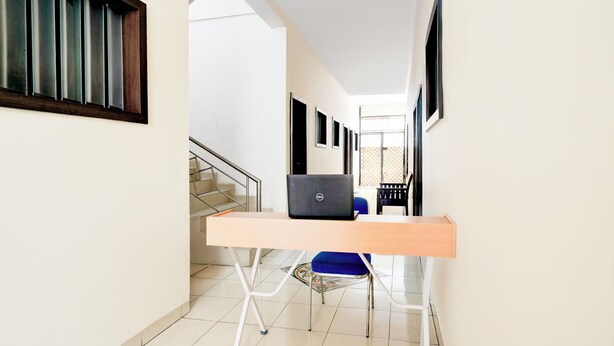 Un pasillo con un escritorio, una silla, una computadora portátil y una escalera.