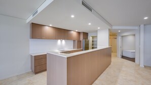 A modern kitchen with wooden cabinets, a central island, and built-in appliances. - Casa Di Marco Polo - 3 Bedroom Apartment (Mandurah)