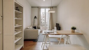 Ein modernes, minimalistisches Wohnzimmer mit einer Couch, einem Esstisch und einer weißen Regaleinheit.