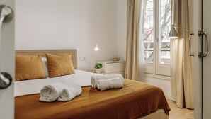 Une chambre d’hôtel avec un lit, une table de chevet, une lampe et une fenêtre avec des rideaux.