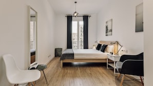 A modern bedroom with a bed, a desk, and two chairs.