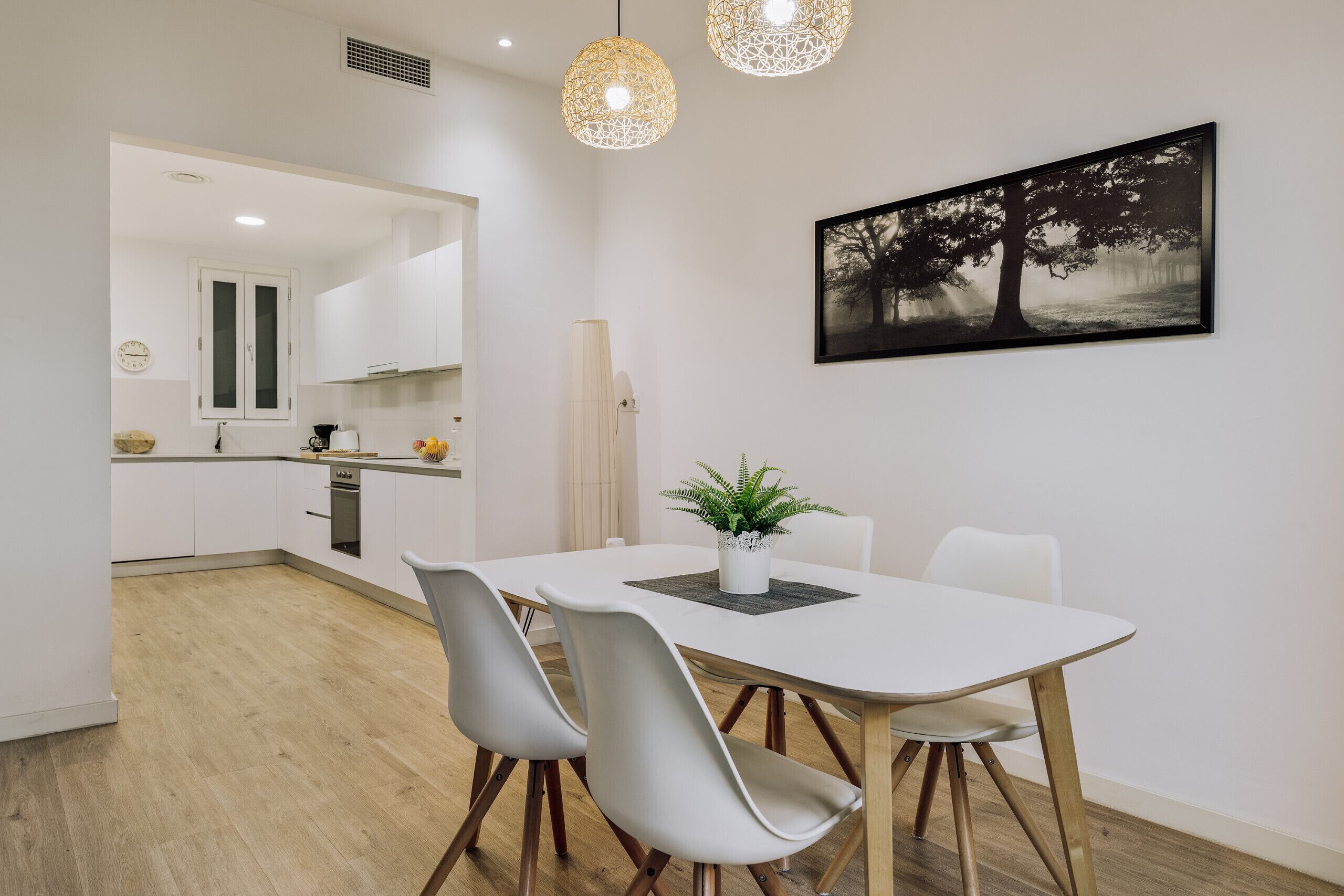 A modern kitchen with white cabinets, a dining table with chairs, and a pendant light fixture.