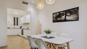 A modern kitchen with white cabinets, a dining table with chairs, and a pendant light fixture.