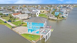 Een pand aan het water met een groot blauw huis, een steiger en een klein bootje.