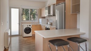 A modern kitchen with a built-in washing machine, a large island with bar stools, and a stainless steel refrigerator.