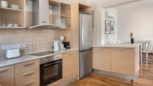 A modern kitchen with a built-in oven, a stainless steel refrigerator, and a coffee maker on the counter.