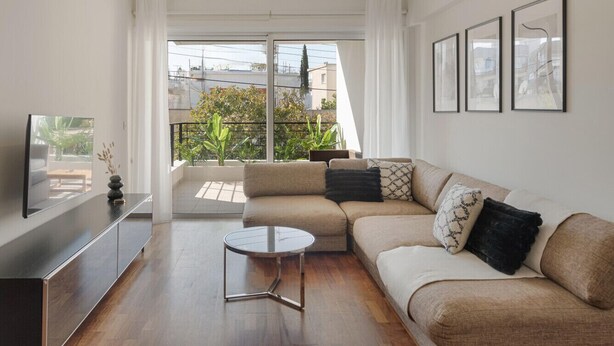 A modern living room with a sofa, a coffee table, and a TV on a stand.