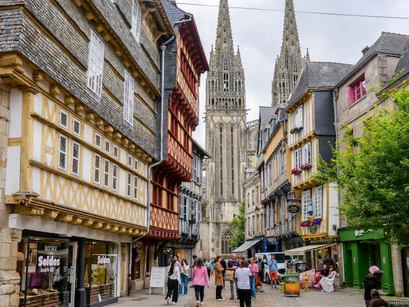 A historic street with traditional half-timbered buildings and a Gothic cathedral in the background.