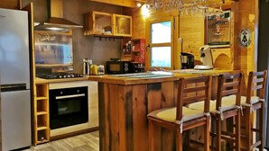 A cozy kitchen with wooden cabinets, a built-in oven, a microwave, and a bar area with stools.