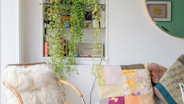 A cozy living room with a white sofa, a wicker chair, and a bookshelf with plants. - Behind the Stained Glass, by Veeve (Paris)