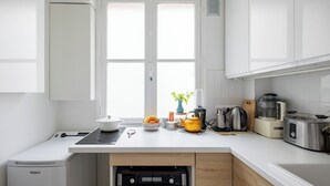 A modern kitchen with white cabinets, a built-in oven, a coffee maker, and a toaster. - Behind the Stained Glass, by Veeve (Paris)