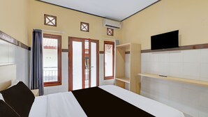 Hotellihuone, jossa on sänky, vaatekaappi ja seinälle asennettu televisio.