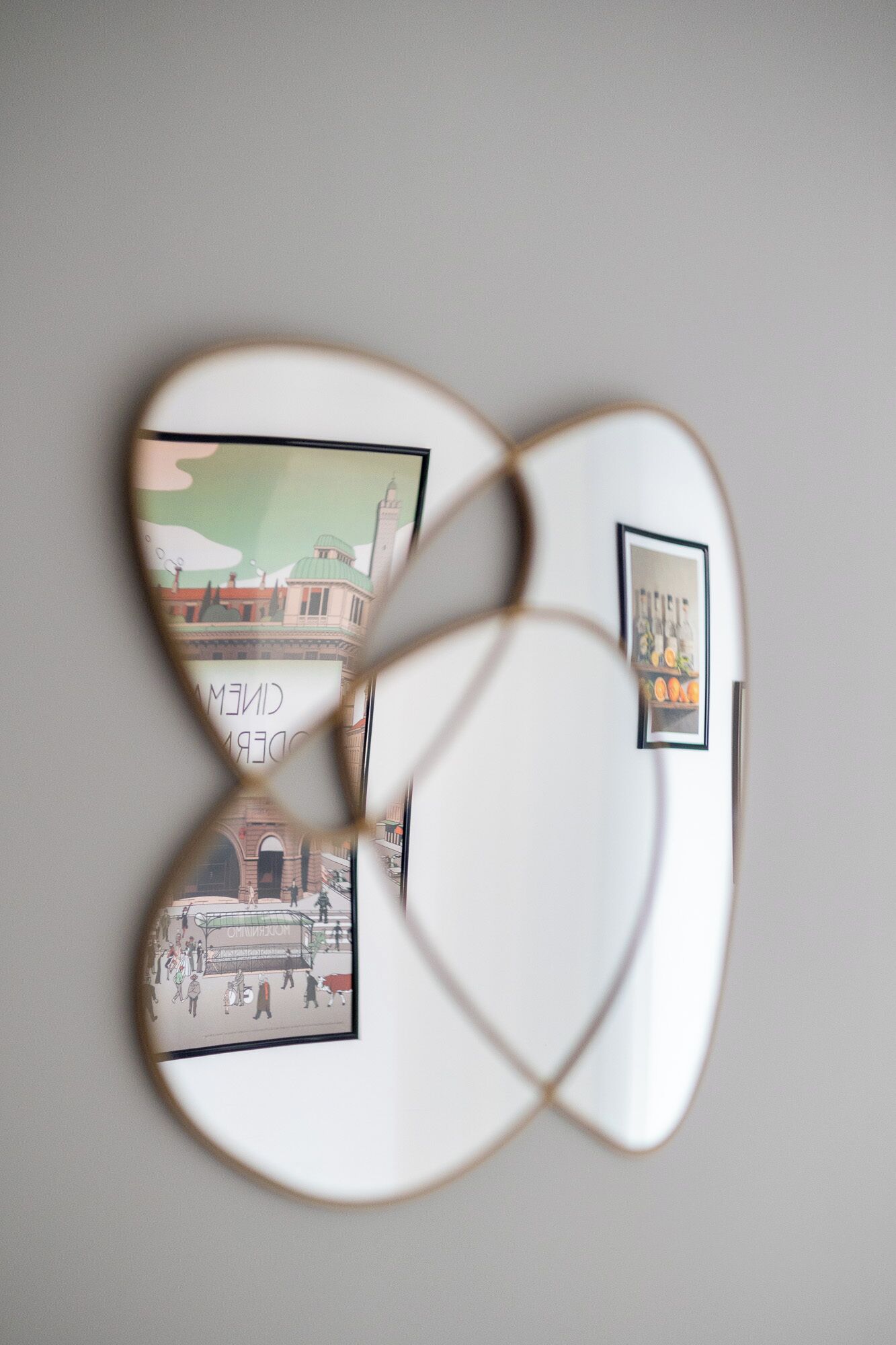 A wall with a geometric mirror design and two framed pictures.