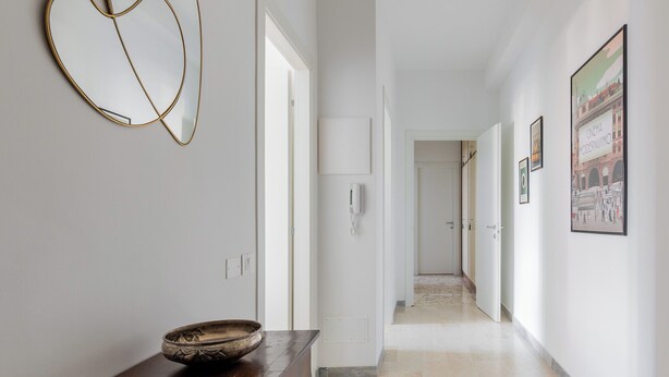 A hallway with a wooden table, a bowl, and a wall-mounted phone. There are doors leading to other rooms. - A Casa di Giorgia II by Wonderful Italy (Bologna)
