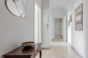 A hallway with a wooden table, a bowl, and a wall-mounted phone. There are doors leading to other rooms.