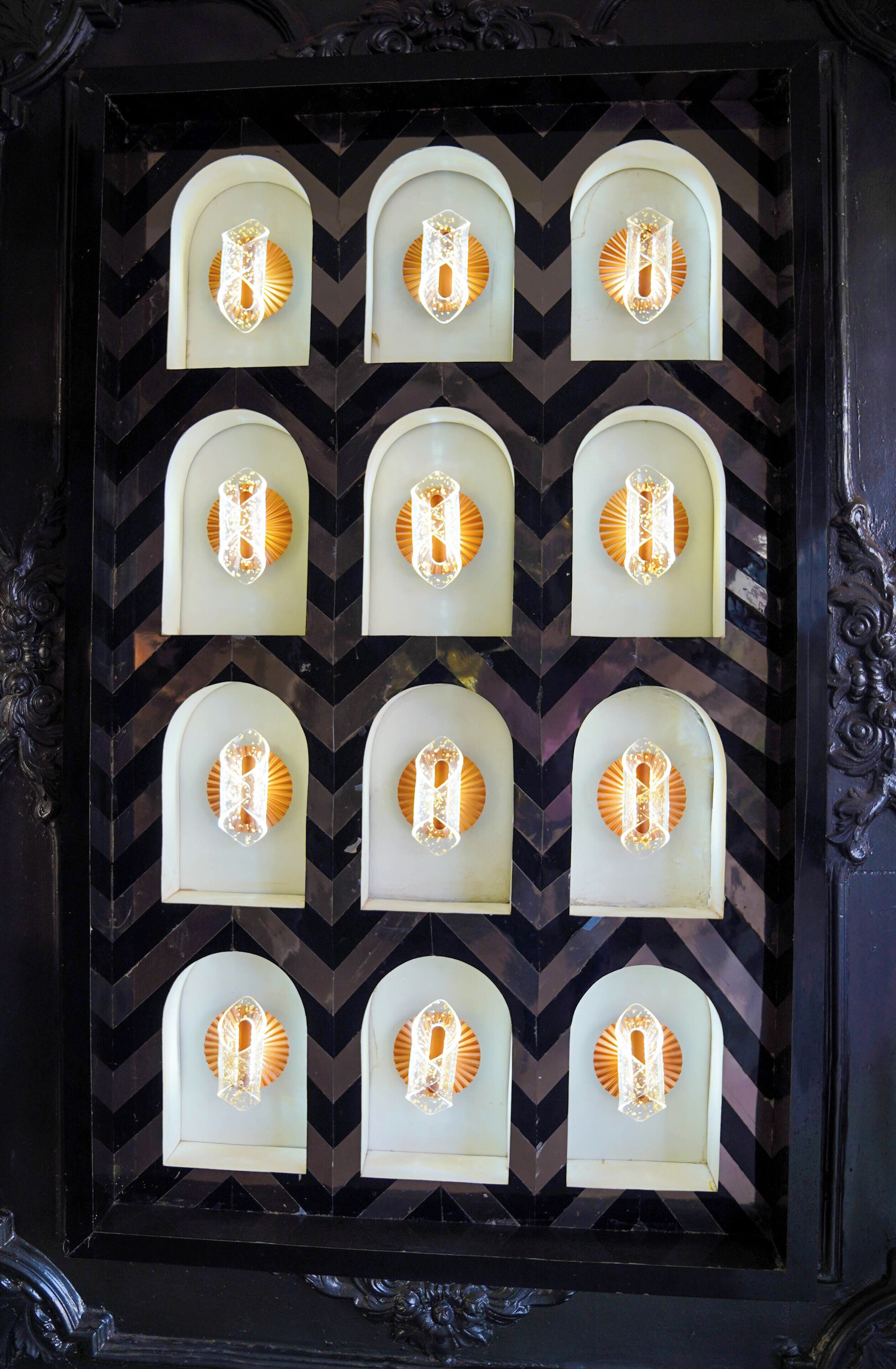 Une composition encadrée présentant des appliques murales illuminées sur un fond à motifs chevrons.