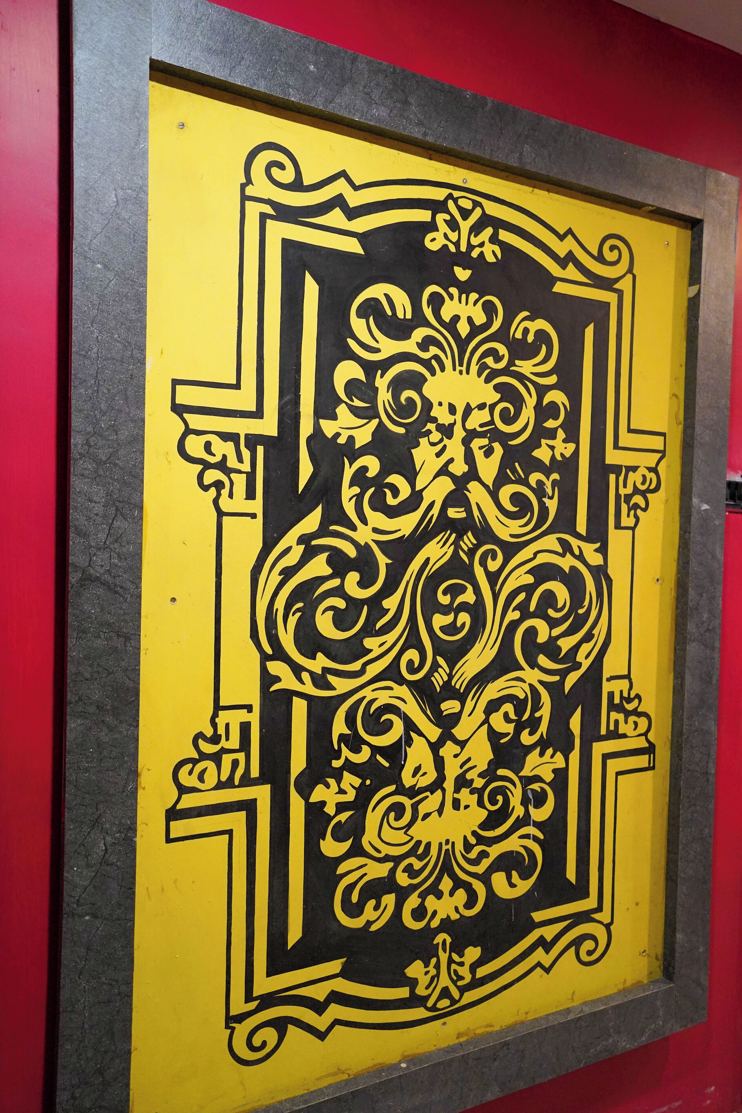Une œuvre d’art encadrée, ornée de motifs complexes en noir et jaune sur un fond jaune.