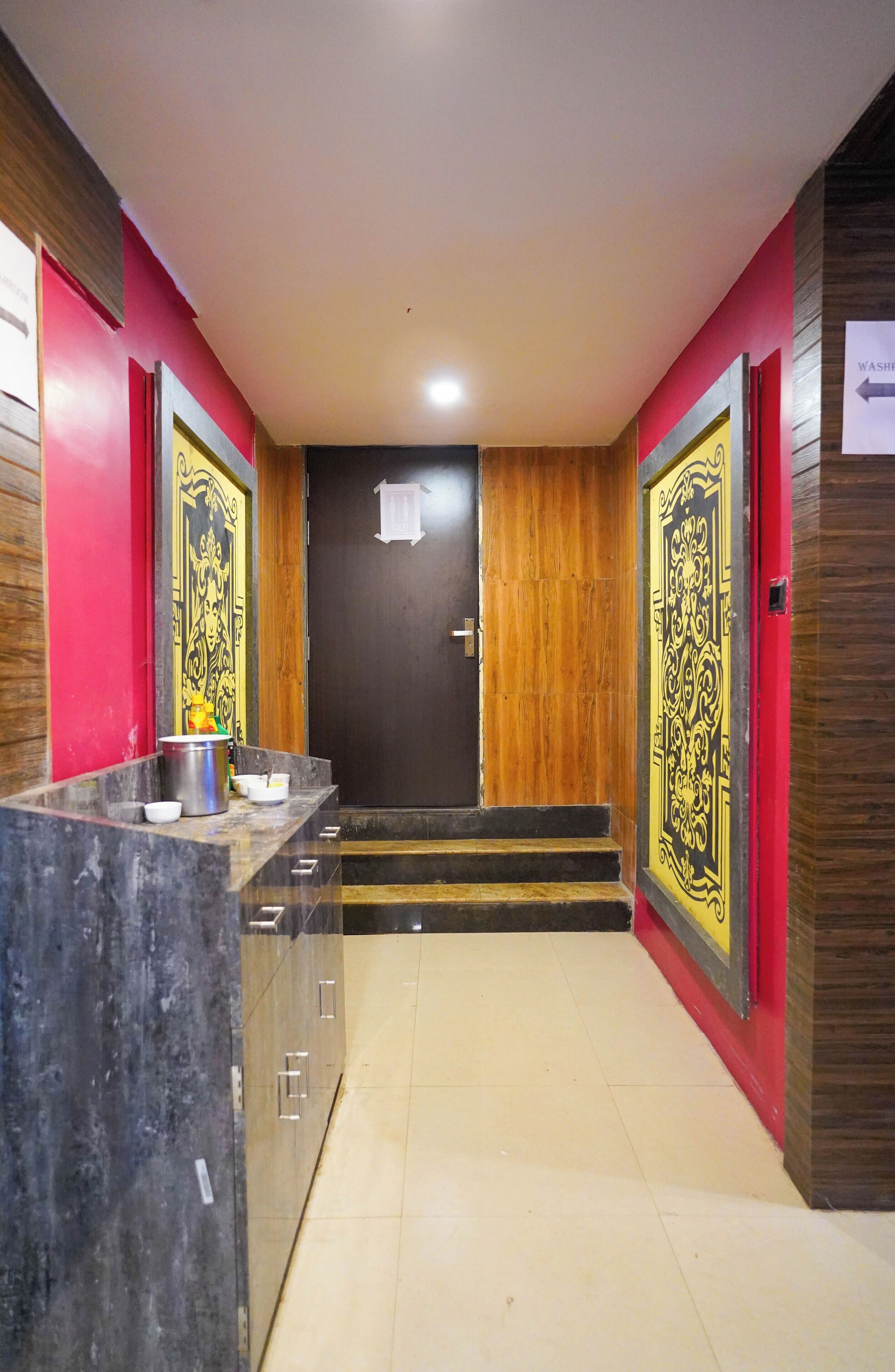A hotel lobby with a marble reception desk, a wooden door with a black and gold design, and a tiled floor.