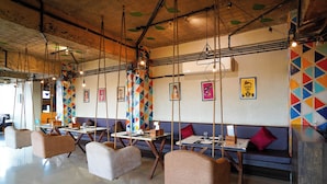 A restaurant with hanging chairs, tables, and colorful geometric wall art. - HOTEL FLORET INN (Durg)