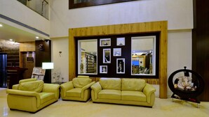 A spacious lobby with a yellow leather sofa set, a wooden accent wall with framed pictures, and a decorative statue. - HOTEL FLORET INN (Durg)
