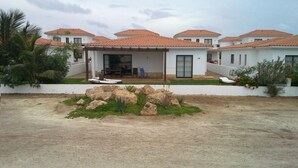 Eine moderne Villa mit überdachter Terrasse, großen Felsen im Vorgarten und weißer Fassade.