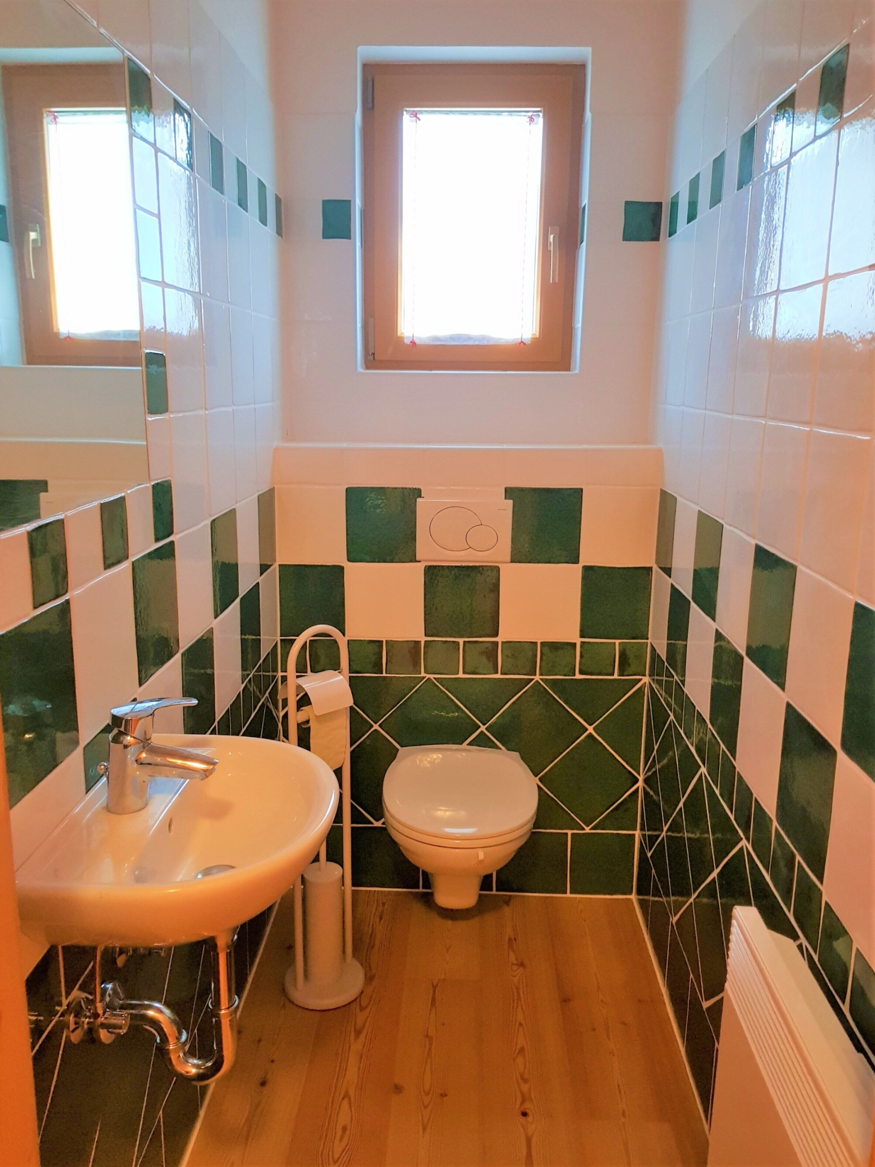 A bathroom with a sink, toilet, and window.
