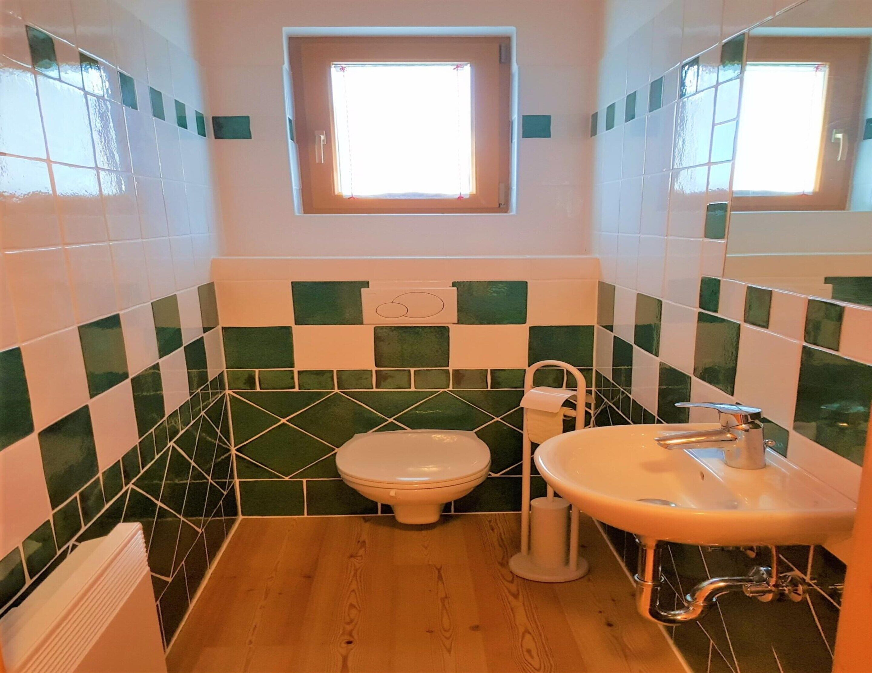 Une salle de bain avec des toilettes, un lavabo et une fenêtre.