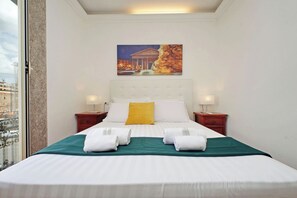 Une chambre d’hôtel avec un grand lit, un tableau au-dessus, et une vue par la fenêtre.