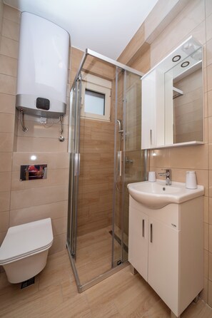 Enjoy a refreshing shower in the walk-in shower with a pedestal sink and large mirror.