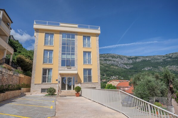 Stunning two-story building with a balcony and large windows, set amidst a picturesque village with mountain views.