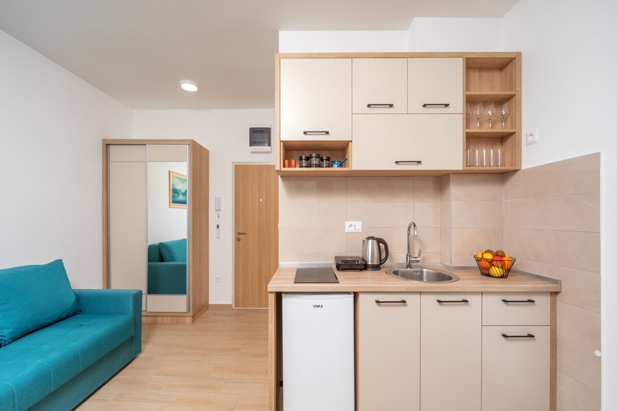 Una cocina compacta con refrigerador, lavamanos y armarios de madera.