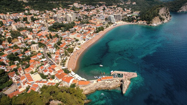 Vista aérea de un pueblo costero con playa, edificios y un litoral rocoso.