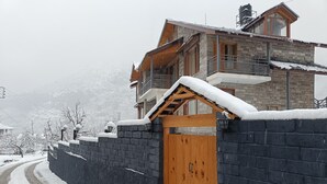 Una zona residencial cubierta de nieve, con un portón de madera y muros de piedra.