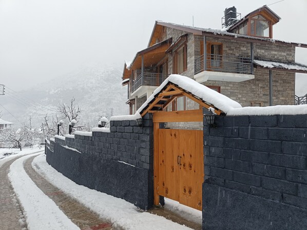 A snow-covered residential area with a wooden gate and stone walls.