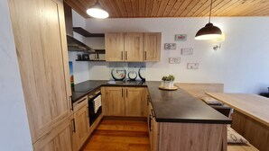 Une cuisine moderne avec des meubles en bois, un îlot central, des luminaires suspendus et des œuvres d’art décoratives sur les murs.
