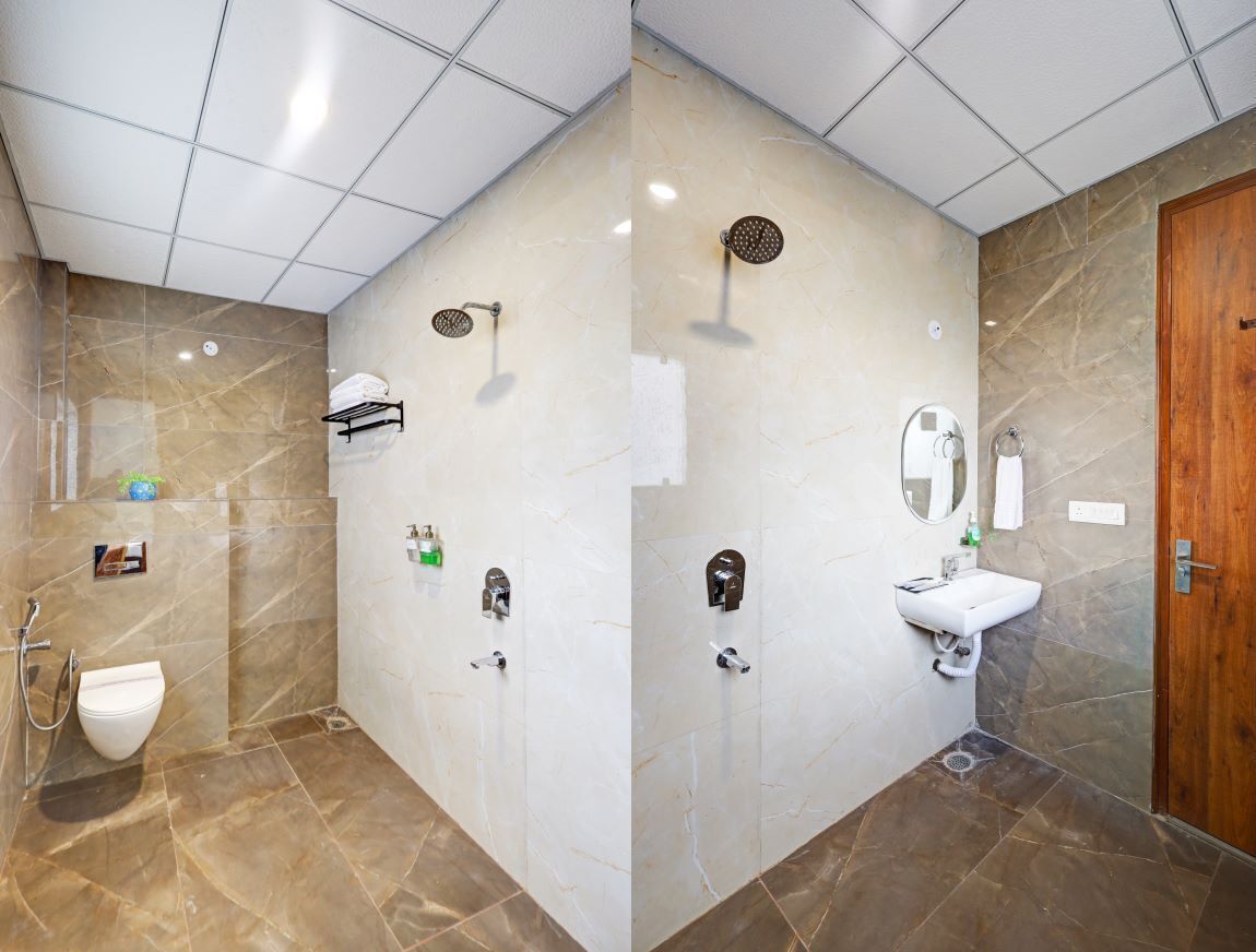 A modern bathroom with a shower, toilet, and sink, featuring marble walls and a wooden door.